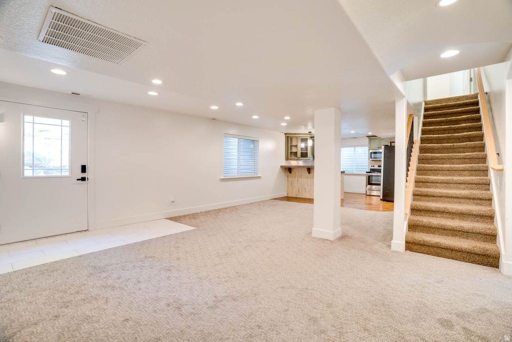 Open living area featuring light-toned carpeting and recessed lighting