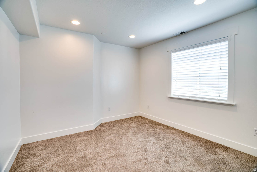 Carpeted room with a single window featuring white blinds and trim