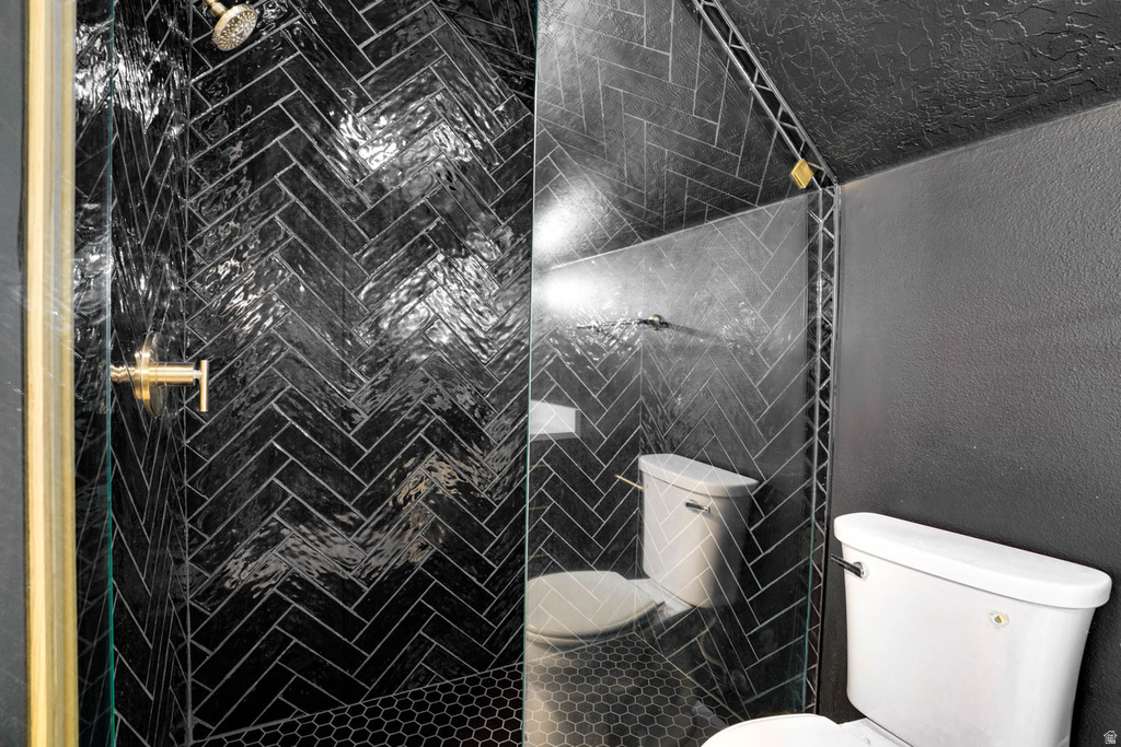 Walk-in shower featuring black herringbone tile, a gold-finish shower head, and gold-finish fixtures