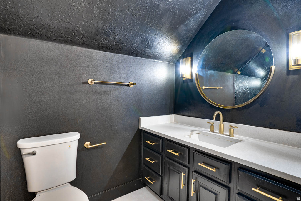 Bathroom featuring a dark vanity with gold-tone hardware, a white countertop with an integrated sink, and a circular mirror with a gold-tone frame