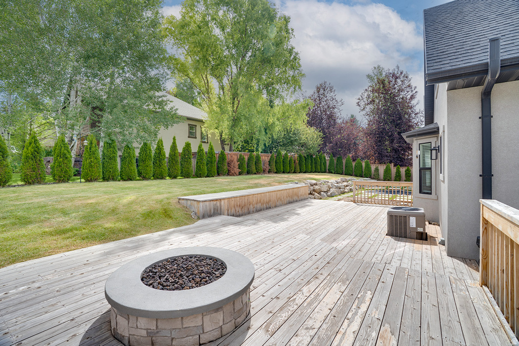 Expansive wood deck featuring a built-in fire pit with stone surround and a raised wood planter box