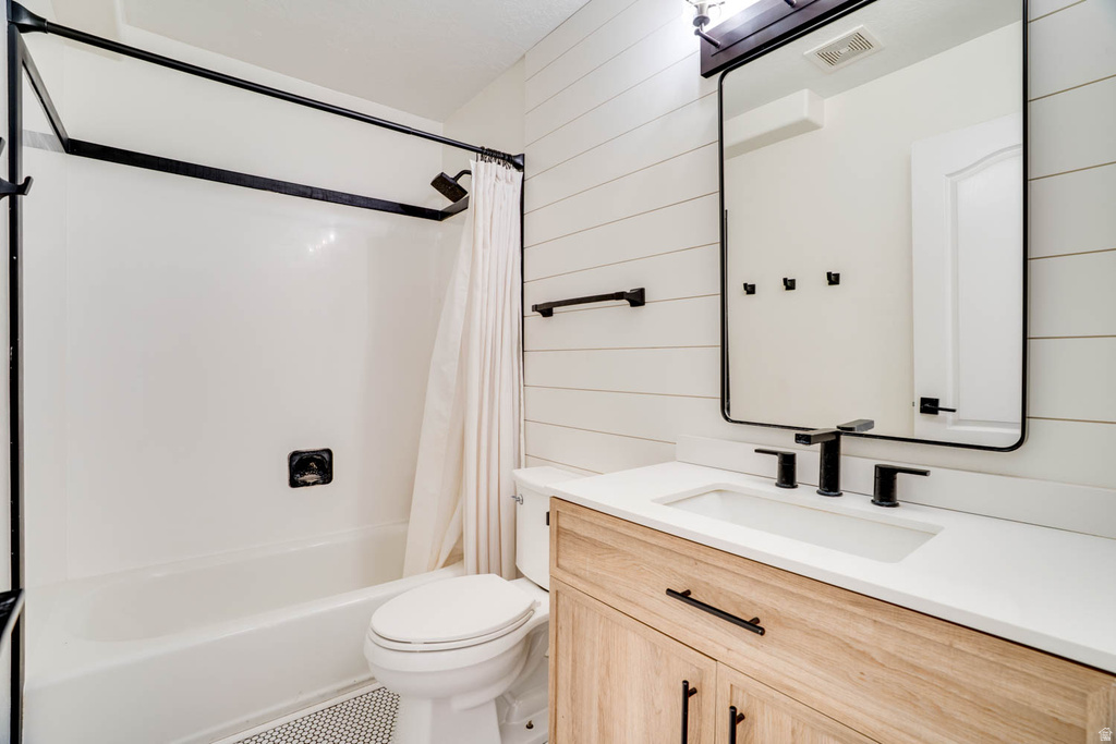 Bathroom featuring a white bathtub/shower combination with black fixtures, a wood-finish vanity with a white countertop and integrated sink, and black hardware