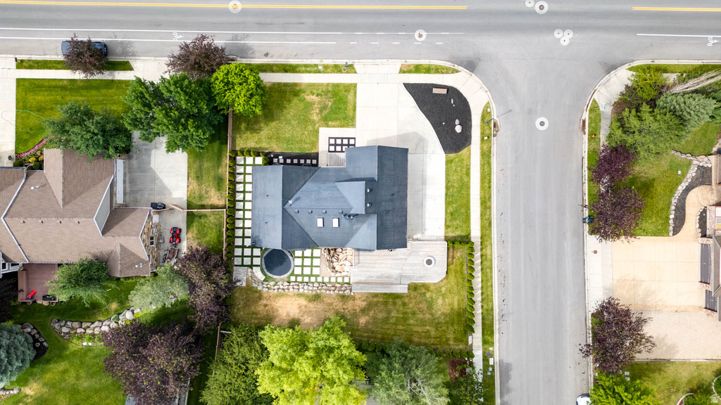 Modern residence featuring a dark-toned roof, an extensive concrete driveway, and a thoughtfully designed landscape with decorative square pavers