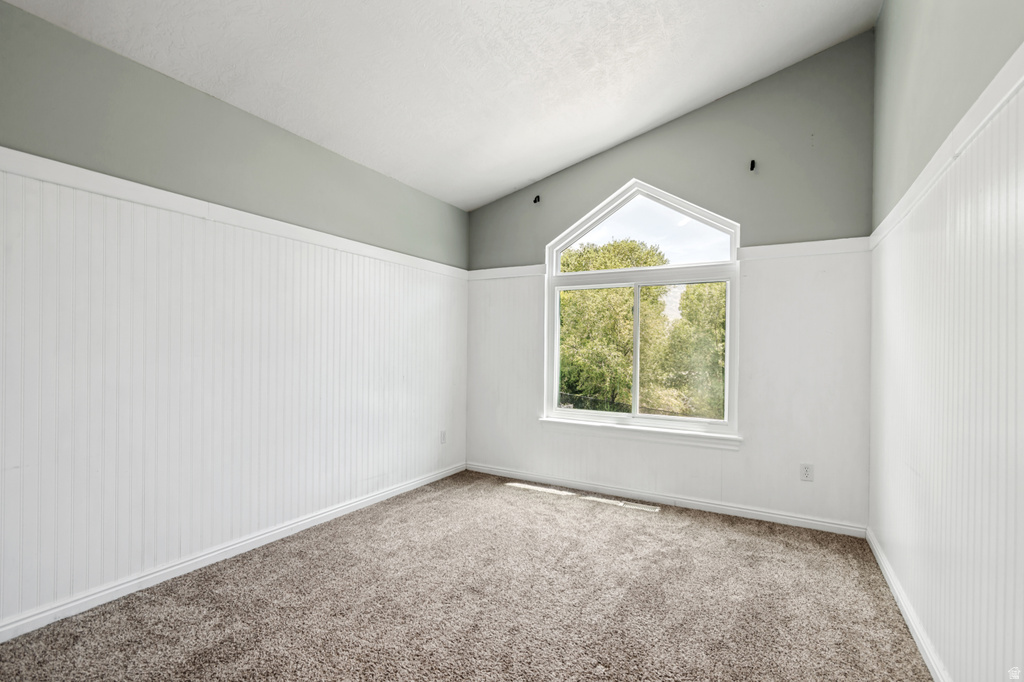 Room featuring a vaulted ceiling and an arched window