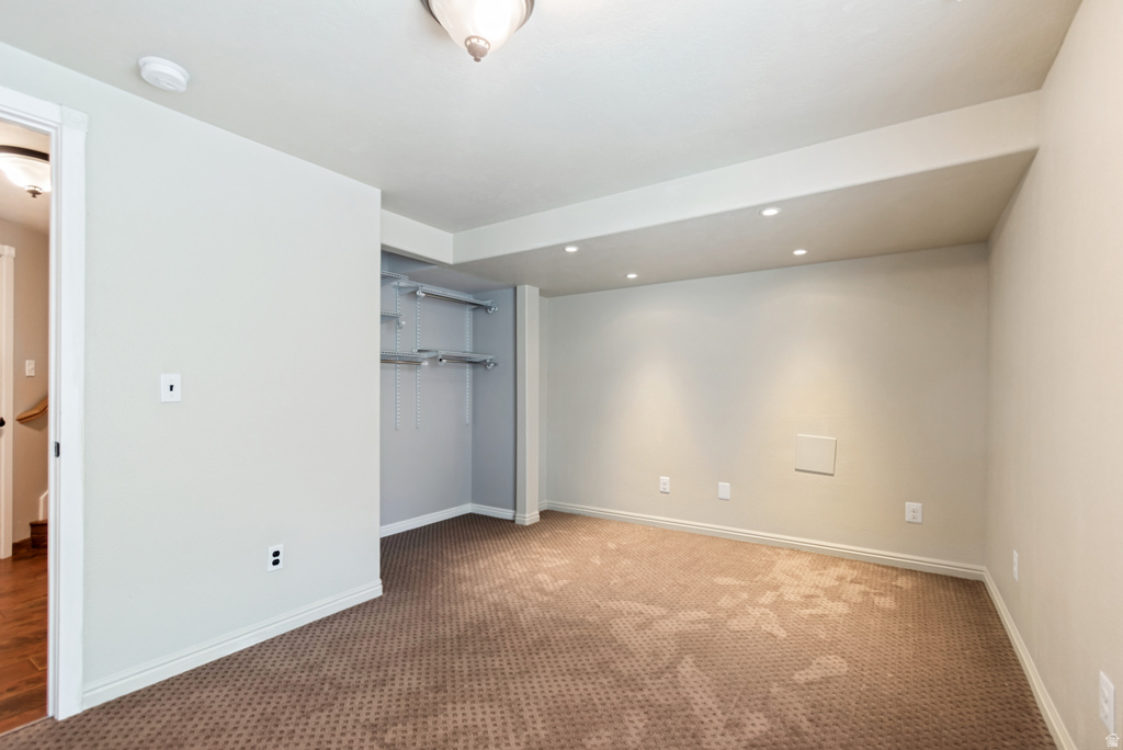 Carpeted room featuring recessed lighting, a built-in closet with shelving and hanging rods, and a neutral color palette