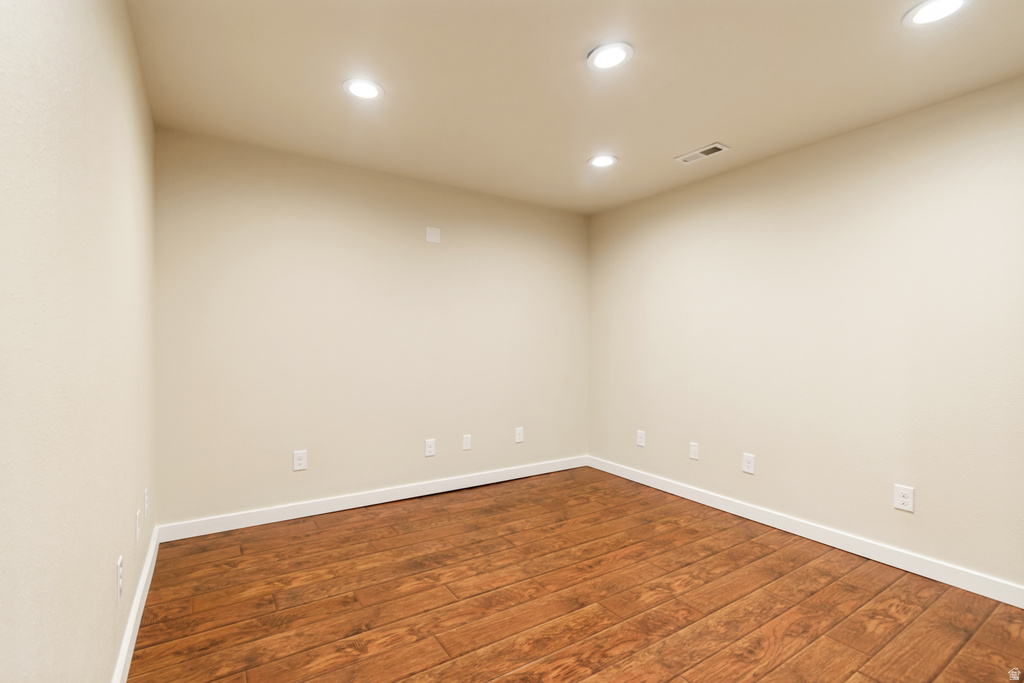 Spacious room featuring wood-finish flooring, recessed lighting, neutral paint, and white baseboards