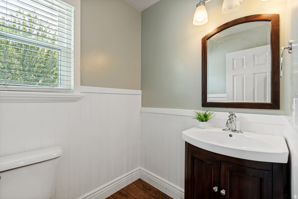Bathroom featuring a wood-finish floor, wainscoting, and a window with blinds