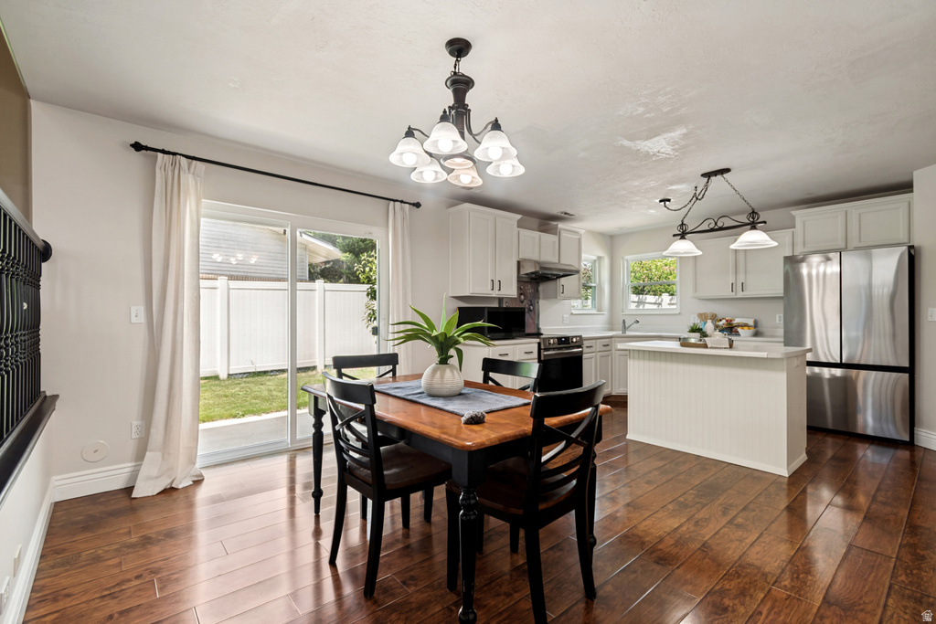Open-concept dining area and kitchen featuring wood-finish flooring, white cabinetry, a kitchen island with beadboard paneling, and stainless steel appliances