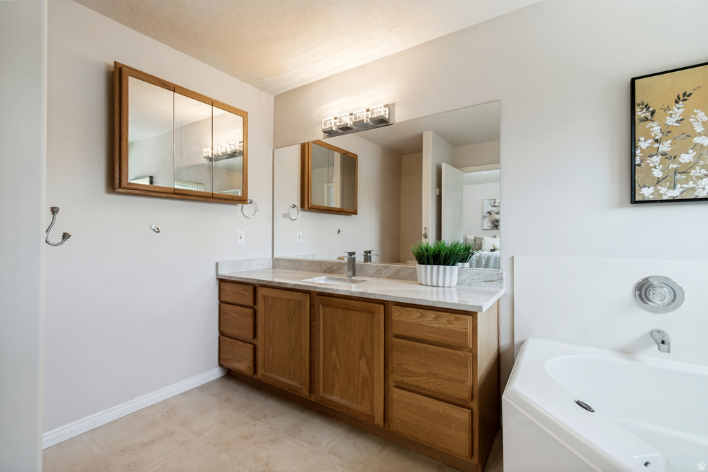 Bathroom featuring a light wood-finish vanity with a light-toned countertop, an integrated sink, and an overhead vanity light fixture