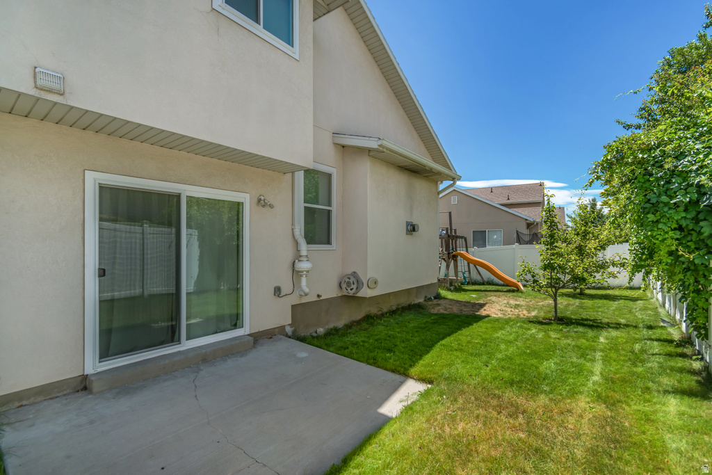 Private backyard featuring a concrete patio, sliding glass door access, and a white picket fence
