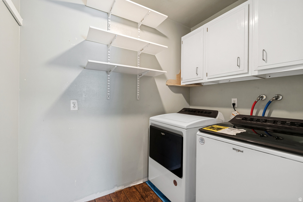Utility area featuring a washer and dryer, upper cabinetry, adjustable shelving, and wood-finish flooring