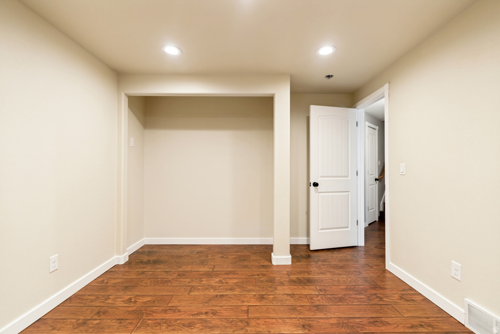 Neutral-toned room featuring wood-finish flooring, white baseboards, and recessed lighting