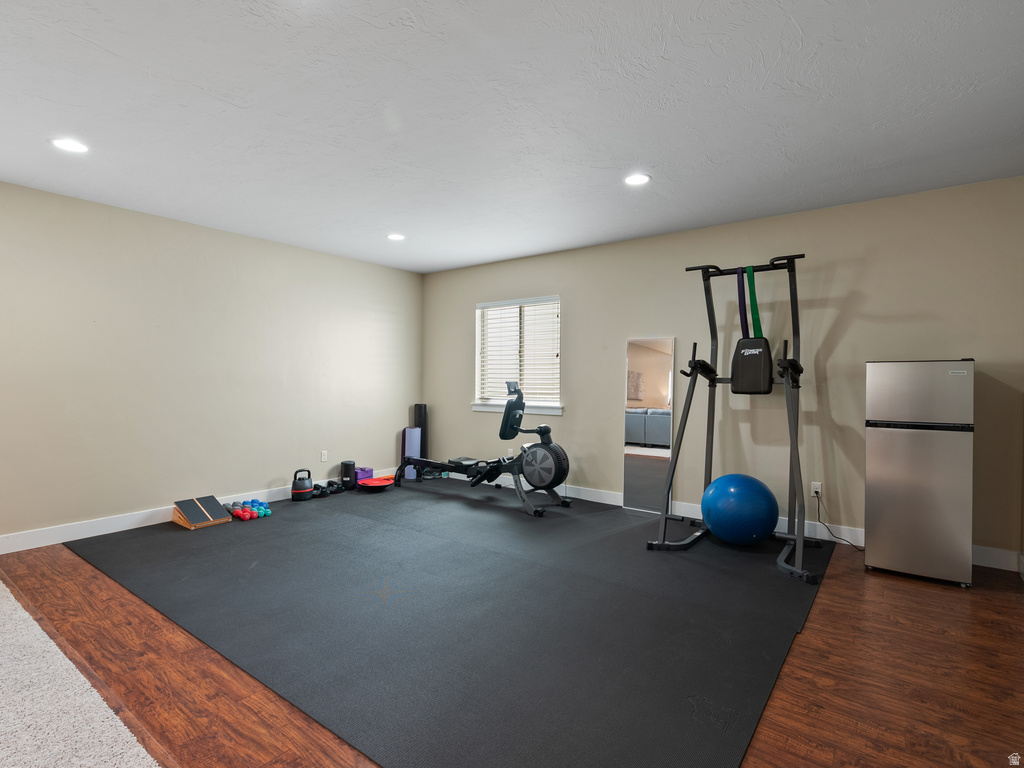 Versatile recreation room featuring recessed lighting, a window with horizontal blinds, and a durable rubber mat flooring section