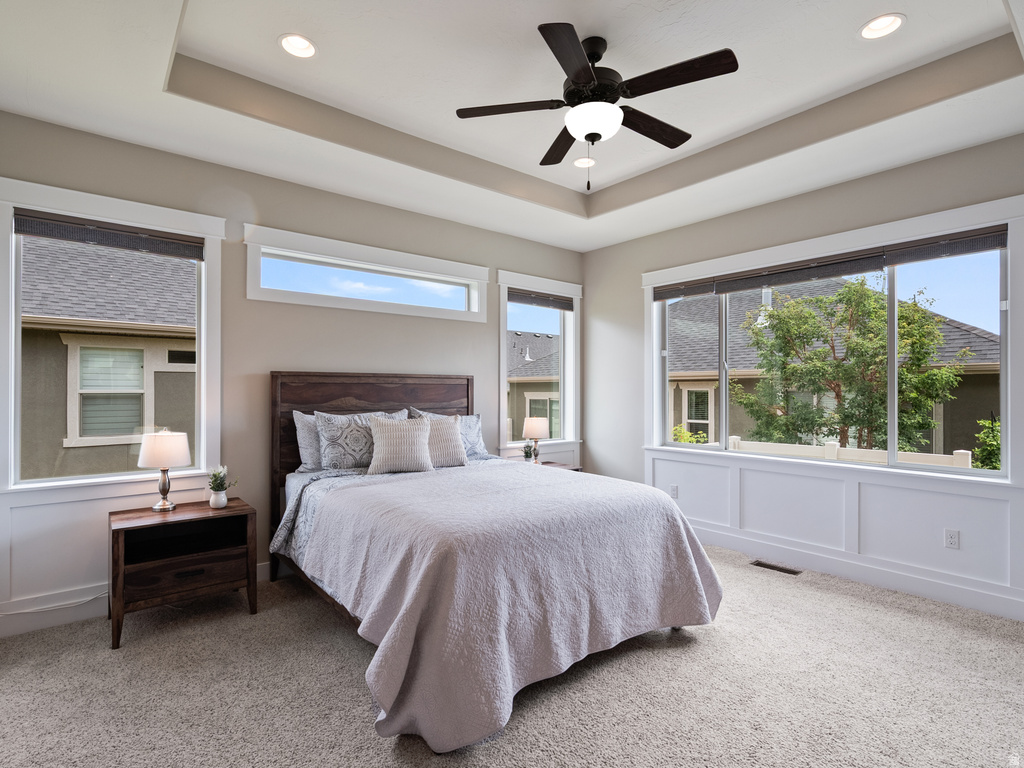 Carpeted room featuring a tray ceiling with recessed lighting and a ceiling fan