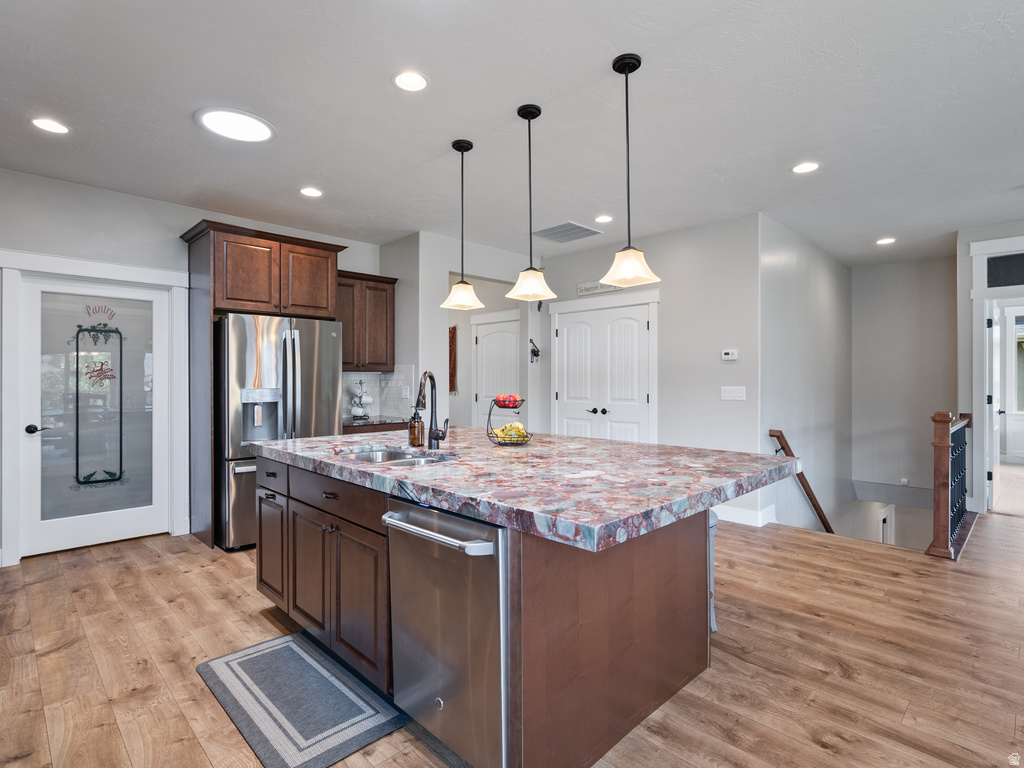 Kitchen island featuring a substantial countertop, integrated sink with gooseneck faucet, and pendant lighting
