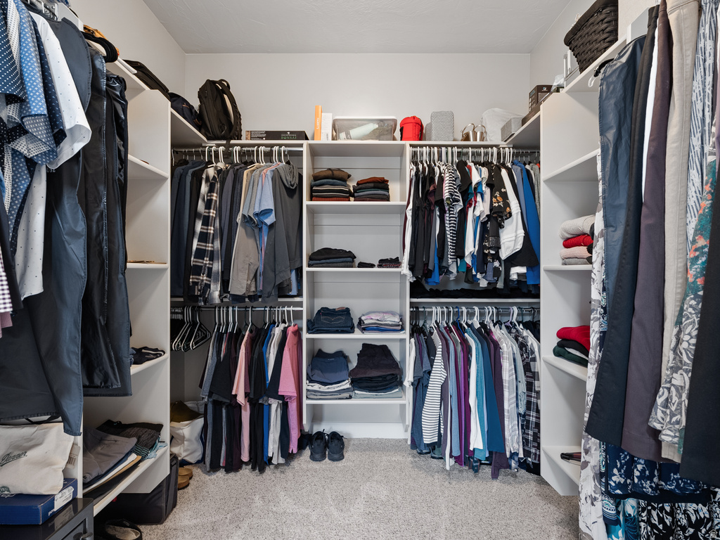 Walk-in closet featuring white built-in shelving, multiple hanging rods, and an integrated storage system