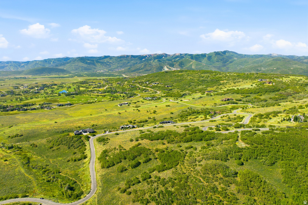 Expansive mountain valley landscape featuring scattered residential properties, winding roads, and abundant green foliage