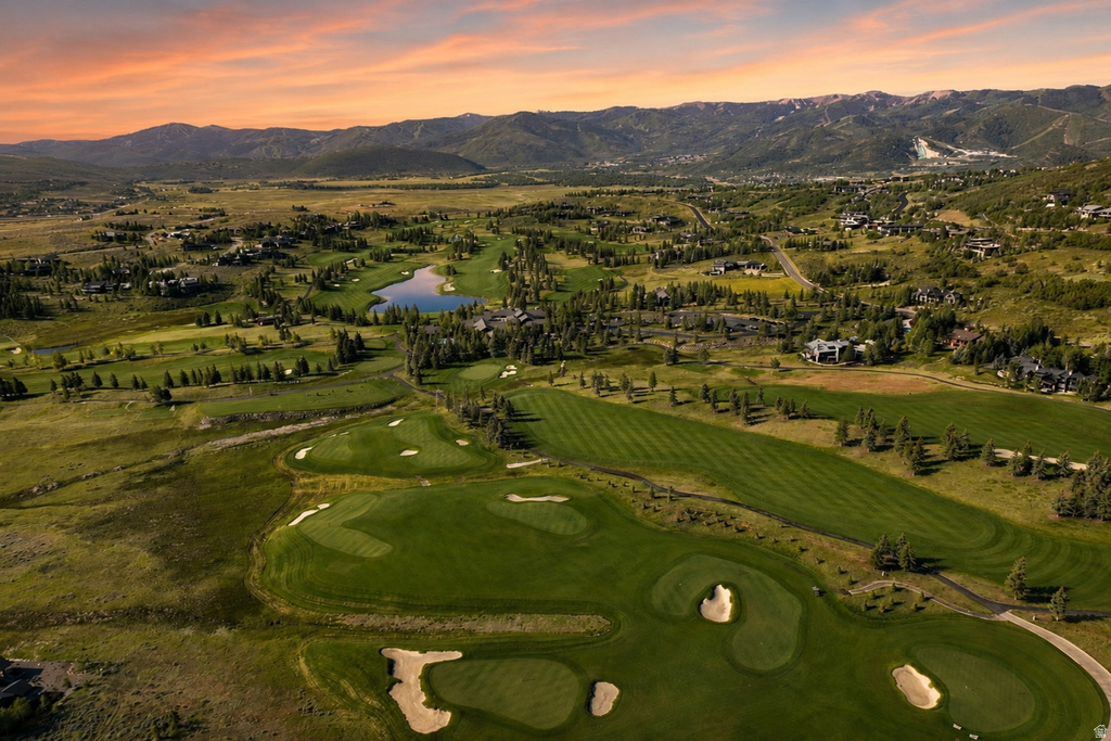 Expansive golf course setting featuring manicured fairways and greens, sand traps, and a central pond