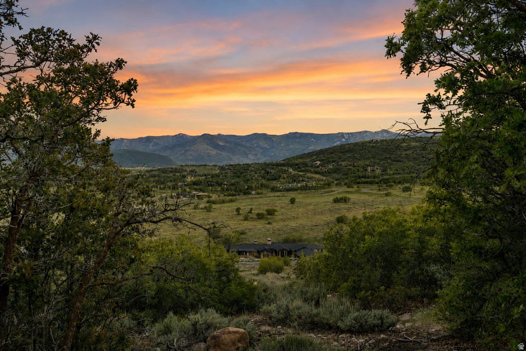 Expansive natural landscape with distant mountain ranges under a colorful sky