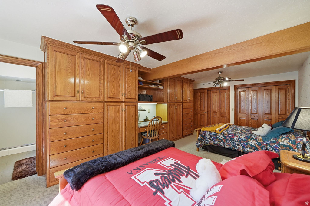 Room featuring extensive built-in wood cabinetry, integrated desk space, and two ceiling fans with lighting