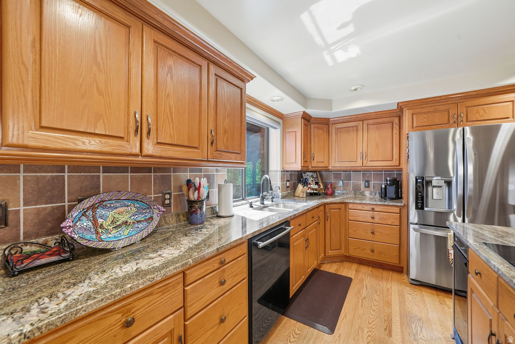 Kitchen featuring natural wood cabinetry, light-toned wood-finish flooring, and a window above the sink