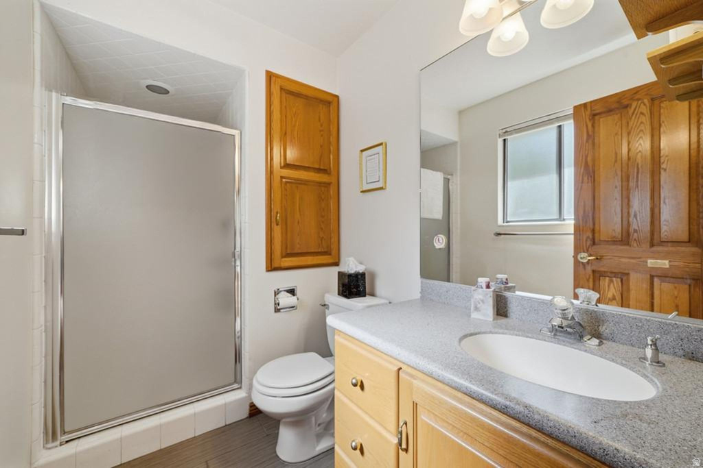 Bathroom featuring a frosted glass shower enclosure, wood-finish vanity with a built-in sink, and a speckled countertop