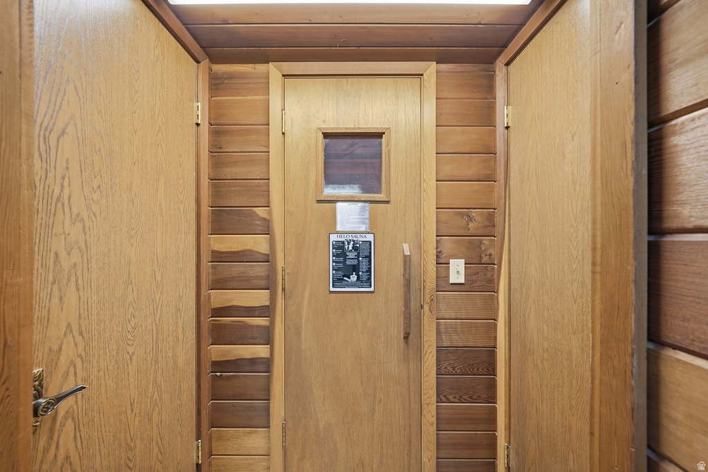 Wood-paneled room featuring a central wood door with a small window, flanked by two additional wood doors