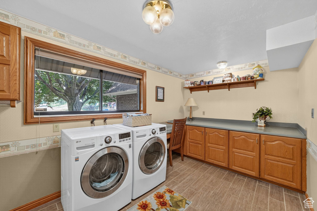 Laundry area featuring wood-finish flooring, a large window with wood trim, and extensive built-in cabinetry with a grey countertop