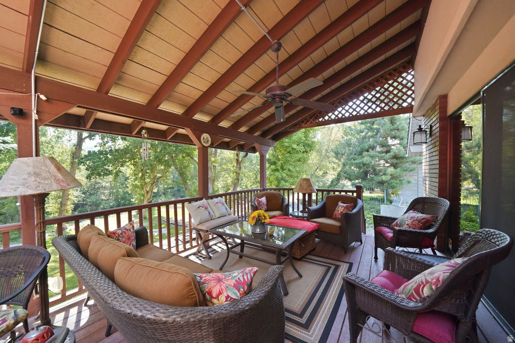Expansive covered wood deck featuring a slatted ceiling, exposed beams, and a ceiling fan