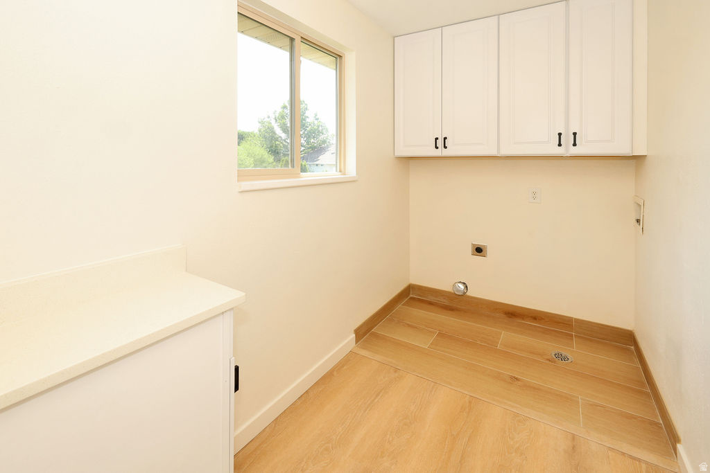 Utility room featuring wood-finish tile flooring, white upper cabinetry with black hardware, and a built-in counter