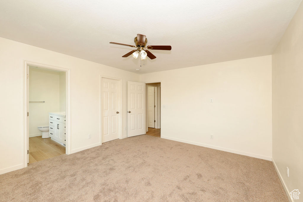 Spacious room with plush carpet flooring, a ceiling fan with light fixture, and neutral wall tones