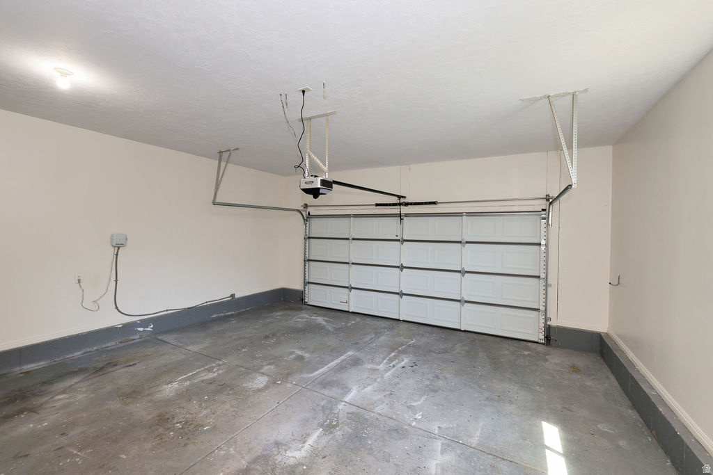 Single-car garage featuring a sectional garage door, concrete flooring, painted walls, and an overhead lighting fixture