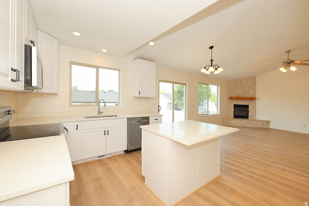 Open-concept living area featuring a kitchen with white cabinetry, stainless steel appliances, and a central island