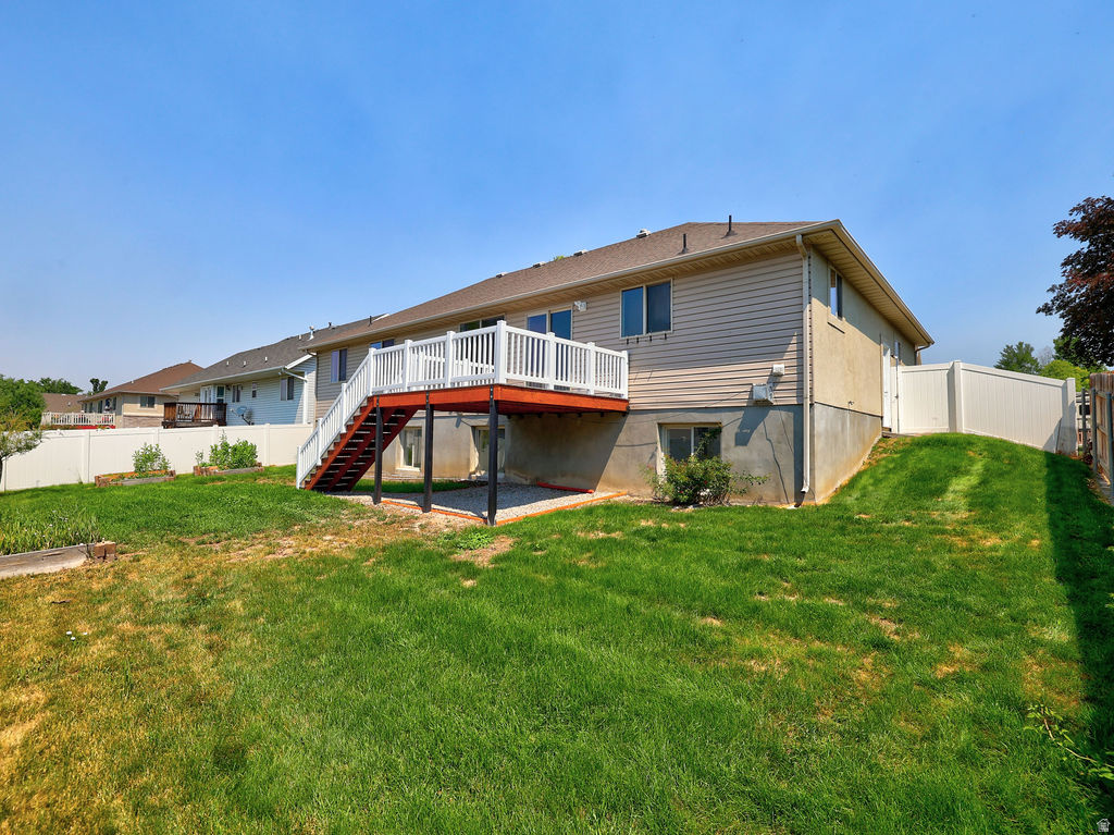 Expansive rear yard featuring a large elevated deck with white railings and red-stained steps