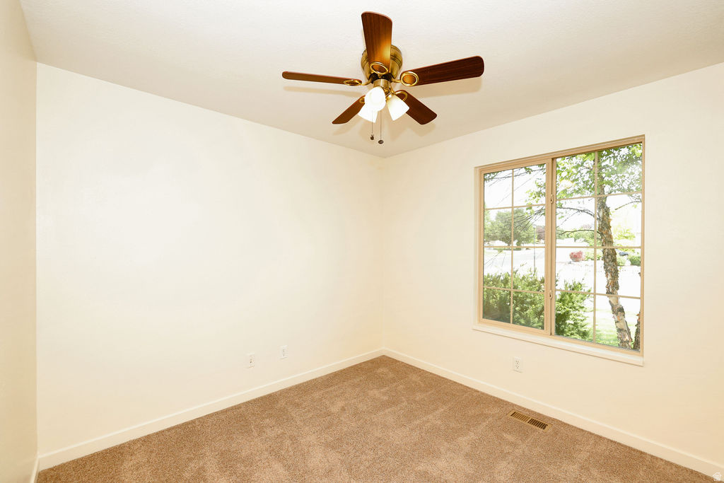 Carpeted room featuring a ceiling fan with integrated lighting, a large window with gridded panes, and natural light