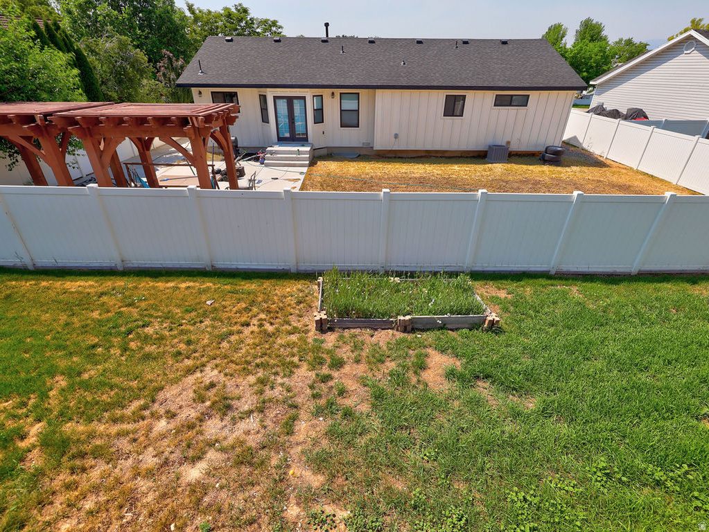 Expansive backyard featuring a white vinyl privacy fence, a raised garden bed, and a wooden pergola structure
