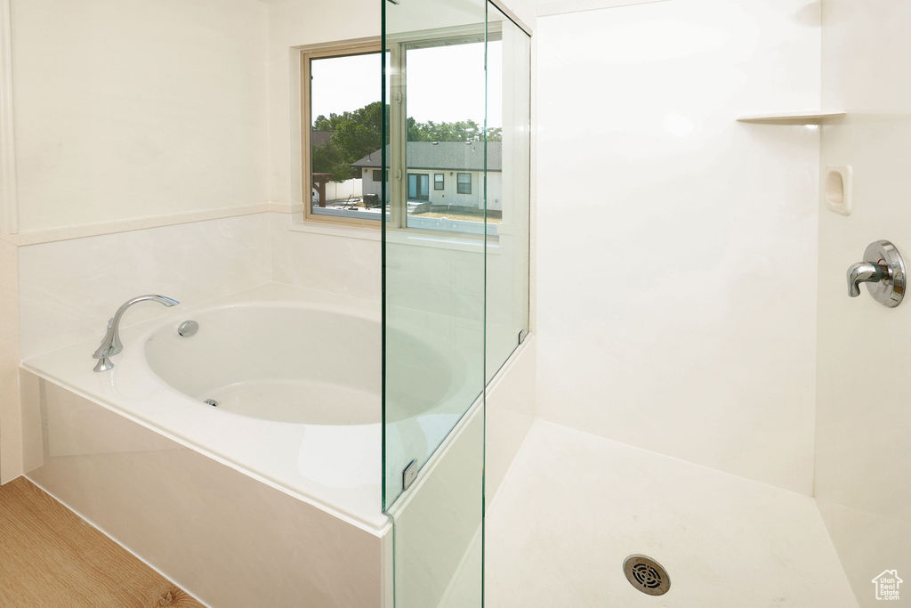 Built-in soaking tub with chrome fixtures, framed by a window, and a glass-enclosed shower featuring a built-in shelf and chrome shower head
