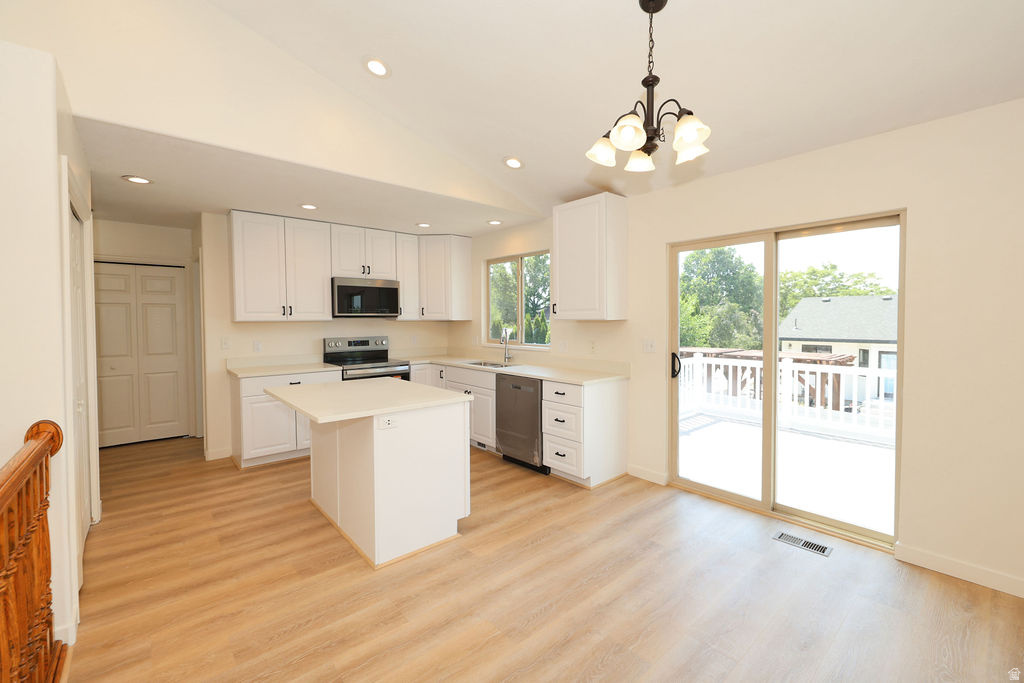 Bright kitchen and dining area featuring white cabinetry, stainless steel appliances, and a central island