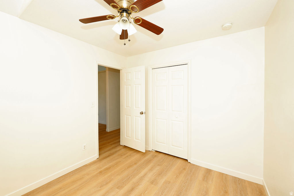 Bright room featuring wood-finish flooring, a ceiling fan with light fixture, white baseboards, and two white panel doors