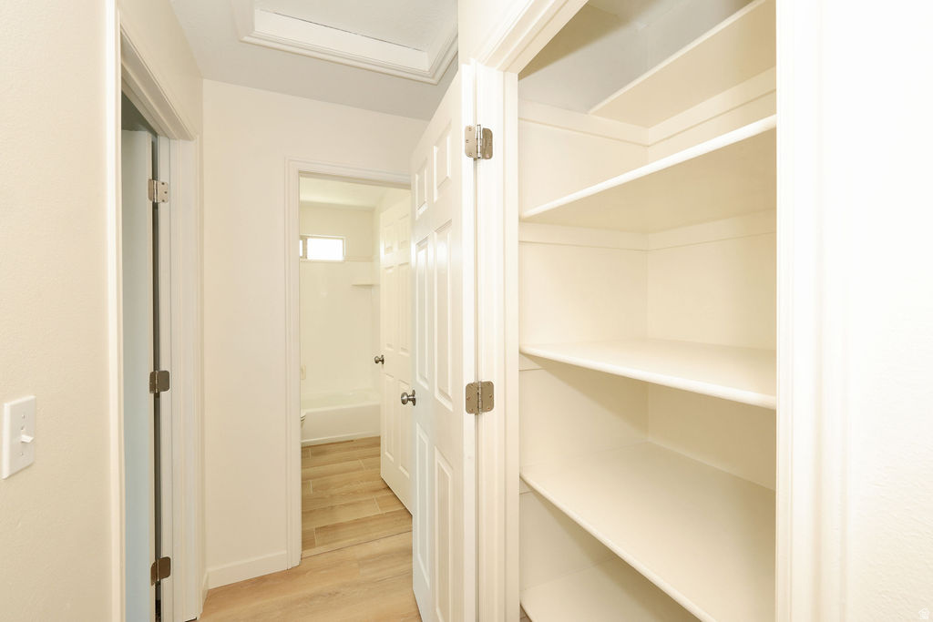 Hallway with integrated shelving unit featuring multiple storage shelves