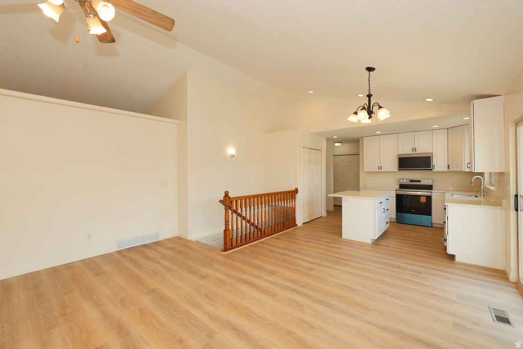 Open-concept living area featuring wood-finish flooring, a vaulted ceiling, and a ceiling fan