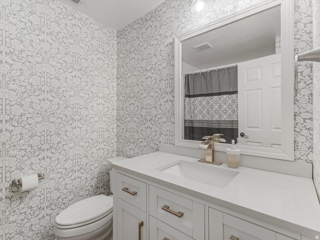 Bathroom featuring a white vanity with recessed panel cabinet doors, brushed gold hardware, an integrated sink, and a white countertop