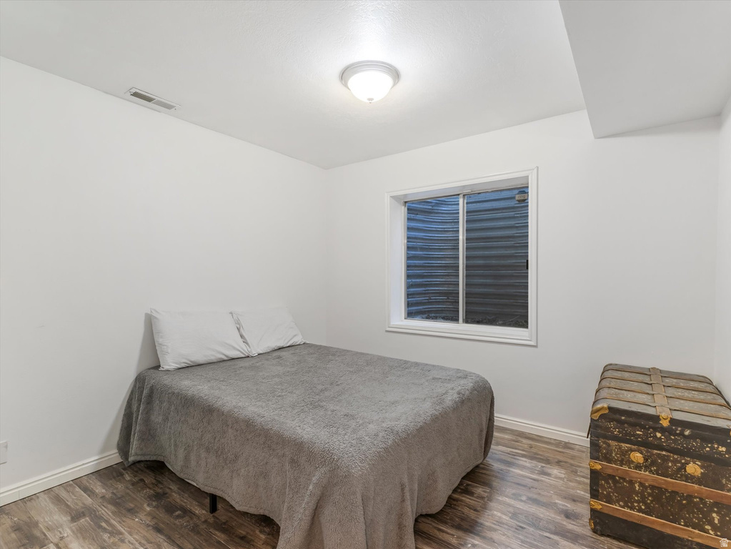 Room featuring a window, wood-finish flooring, white walls, and a ceiling-mounted light fixture