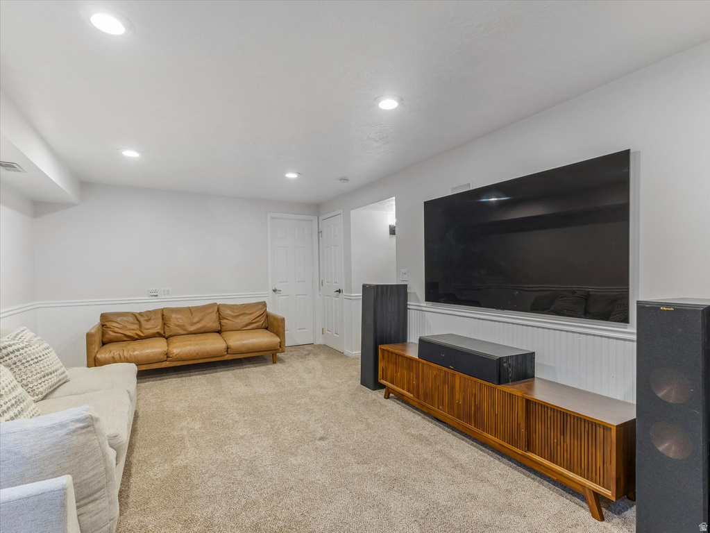 Recessed lighting illuminates this room featuring wall-to-wall carpeting and white wainscoting