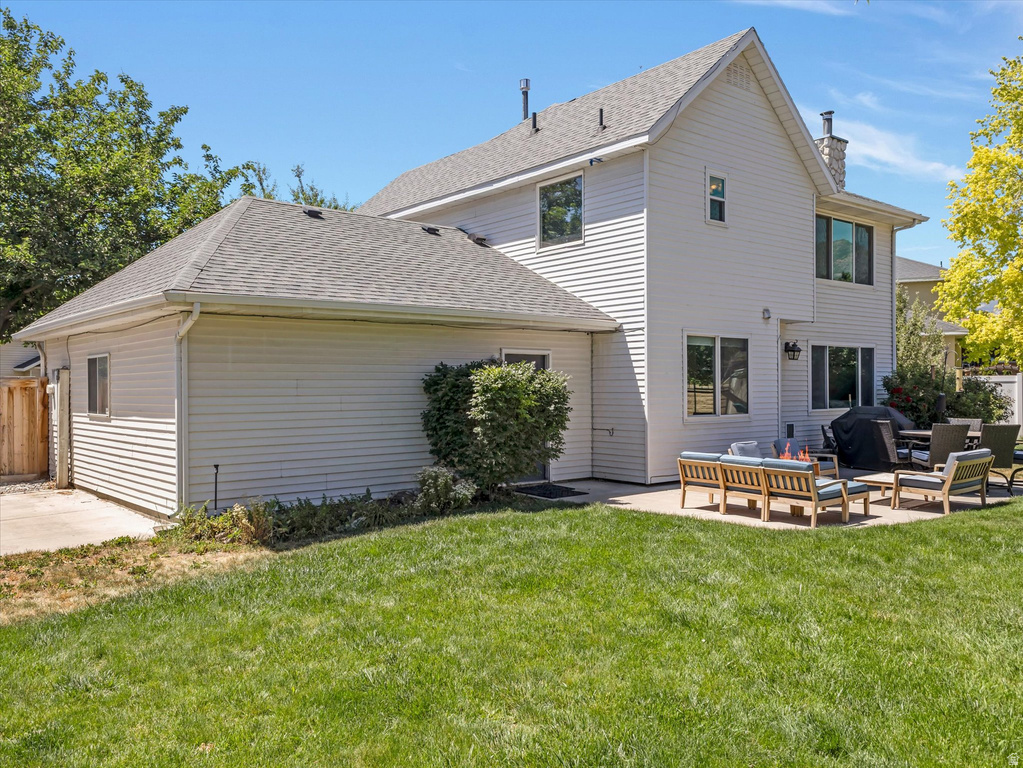 Expansive backyard featuring a manicured lawn, a large concrete patio, and a two-story residence with white siding