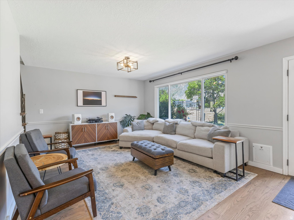 Living area with wood-finish flooring, large window, and crown molding