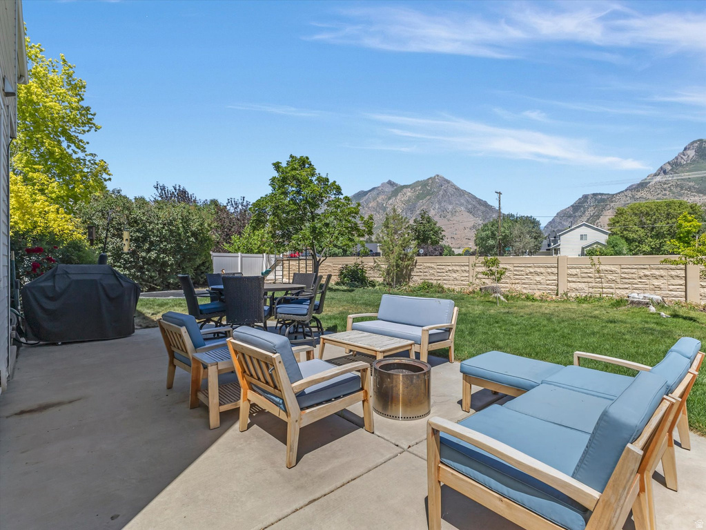 Expansive concrete patio offering multiple seating areas, a rectangular outdoor dining table, and a built-in privacy wall