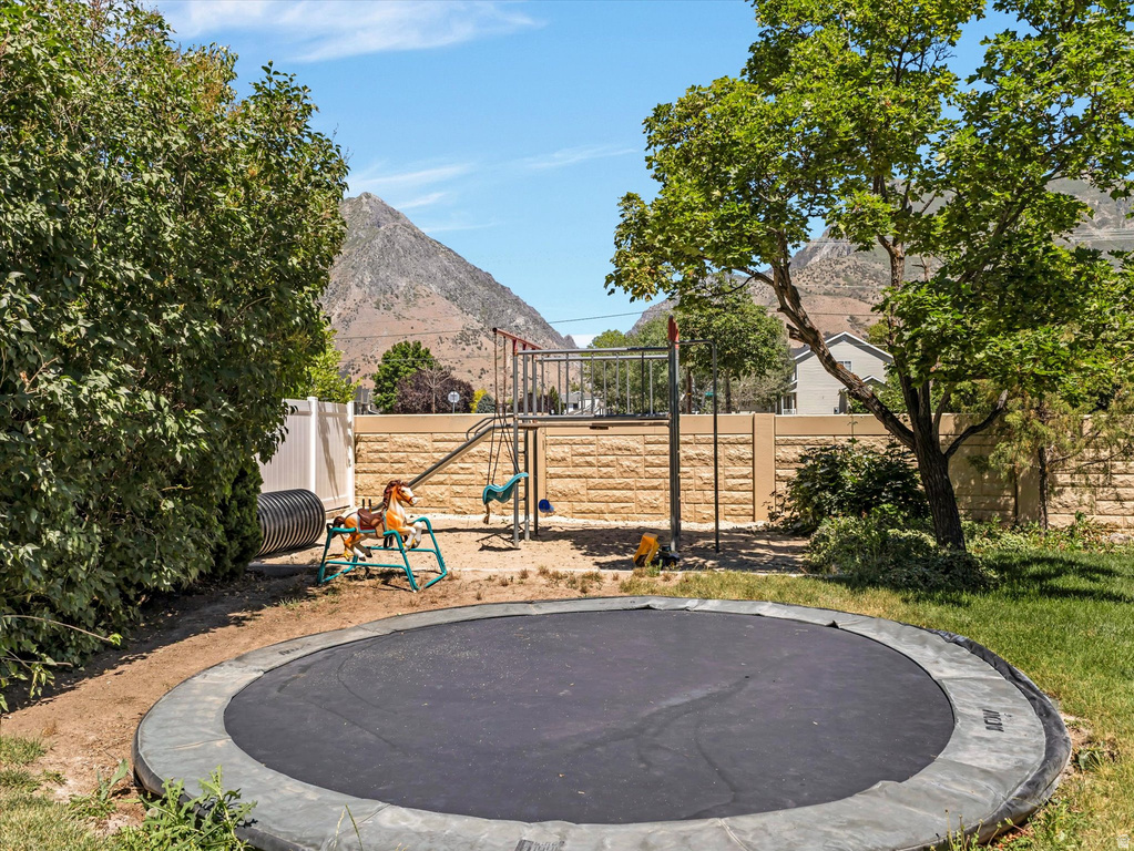 Expansive backyard featuring a built-in trampoline, mature trees, and a textured privacy wall
