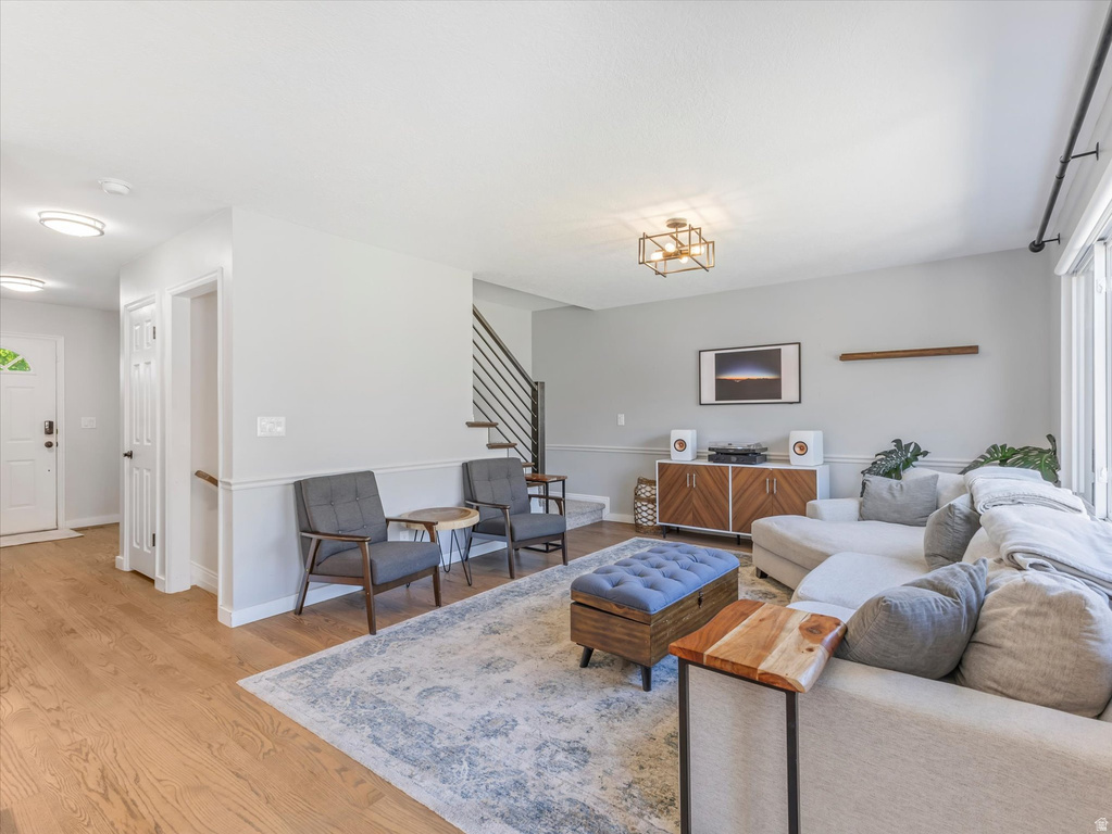 Light wood-finish flooring extends throughout this living area, featuring a modern staircase with open risers and metal railings
