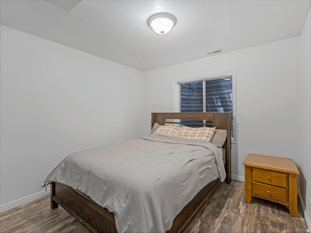 Room featuring wood-finish flooring, a contemporary ceiling light fixture, and a window with a window well